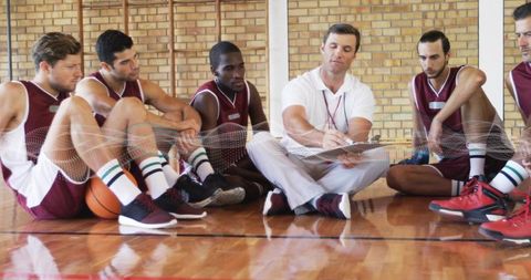Coach leading intense halftime huddle with maroon team on polished indoor basketball court