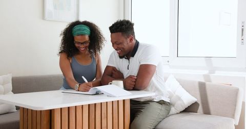 Happy couple planning together while smiling at home