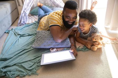 Father and Daughter Smiling Watching Tablet in Cozy Living Room