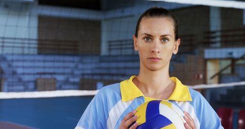 image features a female athlete confidently holding a volleyball in an indoor sports court. ideal for use in sports promotion, athletic inspiration campaigns, and demonstrating team spirit or sports dedication.