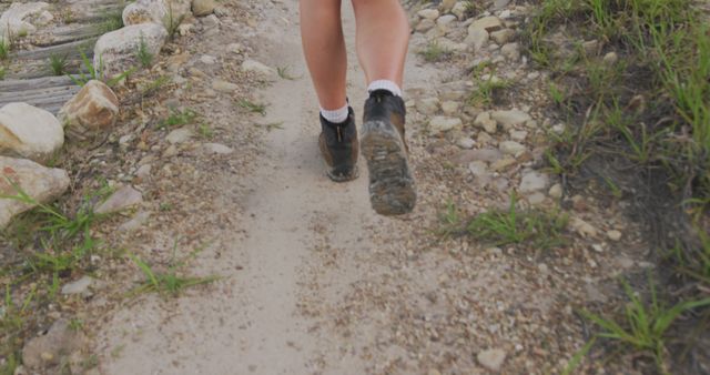 Close-up view of a hiker's legs walking on a rugged rocky trail. This photo can be used for promoting outdoor activities, travel adventures, hiking gear, or fitness content. Perfect for blogs, magazines, advertisements, and social media related to hiking and nature explorations.