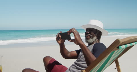 Senior Man Relaxing on Beach Taking Photos with Smartphone