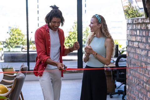 Diverse colleagues celebrating office opening with red ribbon ceremony