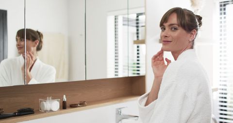 Middle-aged Woman Applying Skincare in Bright Bathroom - Download Free Stock Images Pikwizard.com