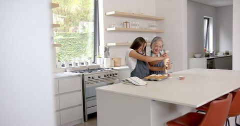 Grandmother and Granddaughter Decorating Cupcakes in Modern Kitchen