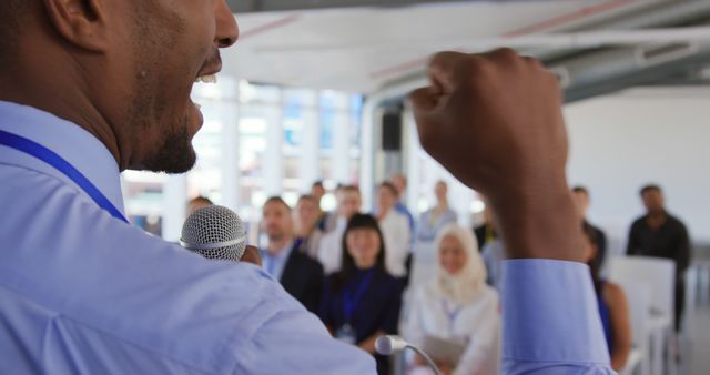 Motivational speaker engaging diverse audience at a business conference. Ideal for use in articles about public speaking, leadership, business seminars, corporate events, and motivational content.