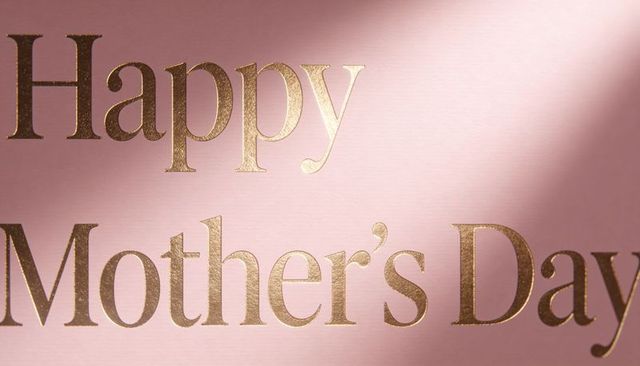 Gold foil happy mother's day lettering on blush pink textured card closeup with shadow