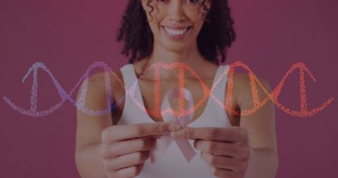 Smiling woman holding pale pink breast cancer ribbon with dna helix overlay for screening