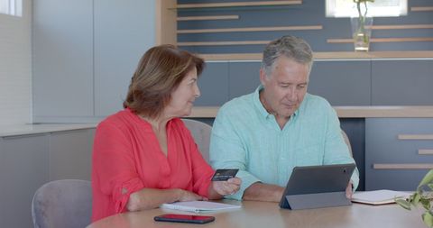 Senior couple expressing joyful contentment in home office discussion