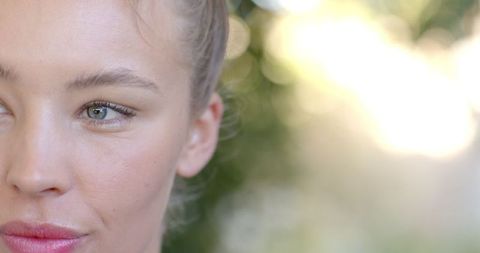 Sunlit Woman Gazing Through Lush Foliage with Focus on Green Eye