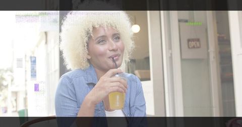 Smiling Woman Enjoying Refreshing Orange Drink at Outdoor Cafe