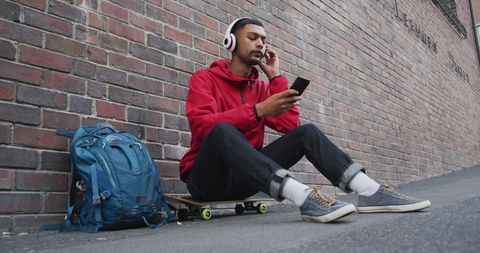 Relaxed Urban Youth Listening to Music by Brick Wall