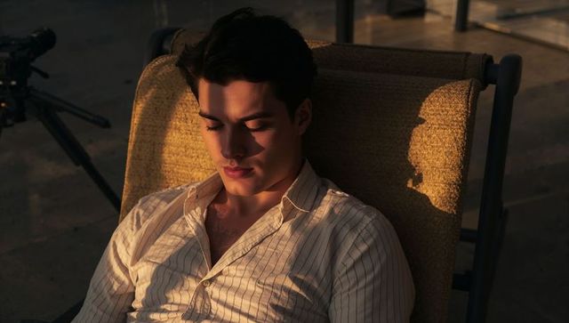 Young Man Relaxing on Rooftop at Golden Hour Wearing Striped Shirt with Telescope