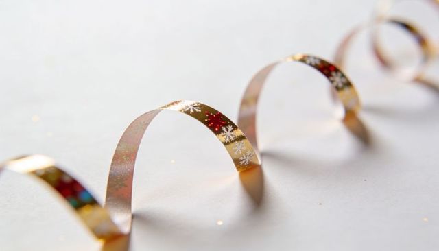 Curving Gold Holographic Ribbon with Snowflake Pattern on White Background