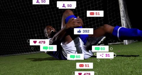 Injured soccer player clutching leg at goal with floating social media reaction icons