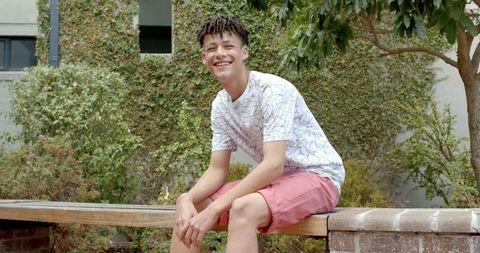 Smiling Teen Sitting Outdoors on Bench in Sunny Garden - Download Free Stock Images Pikwizard.com