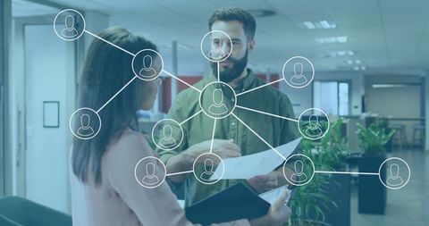 Colleagues in office reviewing documents with digital network graphics