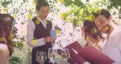 Friends in Outdoor Restaurant Ordering from Waitress with Menus