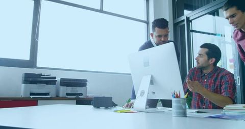 Collaborating team reviewing ui designs on all-in-one desktop in modern creative office