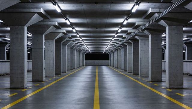 Symmetrical Underground Parking Garage Leading Central Lane Toward Dark Concrete Barrier