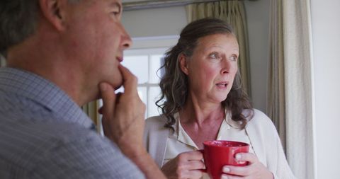 Senior Couple Reflecting by Window with Morning Coffee
