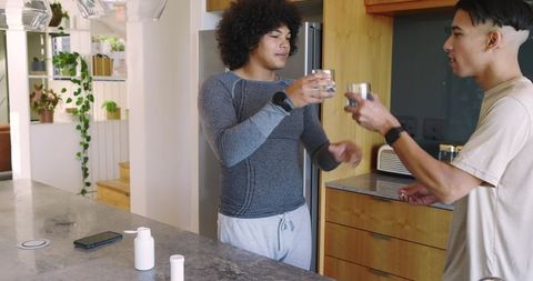 Diverse Friends Celebrating in Modern Kitchen with Health Drinks