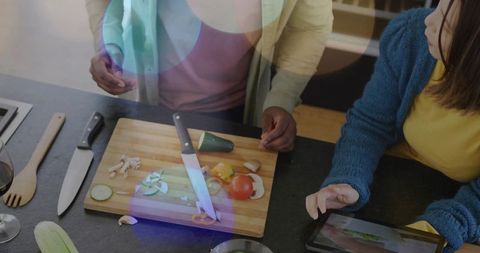 Couple chopping vegetables together at kitchen counter for cozy home dinner with wine