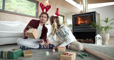 Couple Wrapping Gifts by Warm Fireplace with Antler Headbands