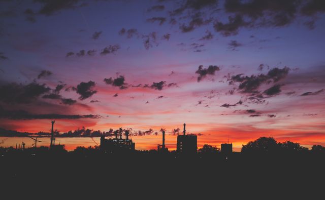 Colorful urban sunset scene showing vibrant clouds, silhouetted buildings and trees. Ideal for backgrounds, travel blogs, city living promotions, or artwork prints.