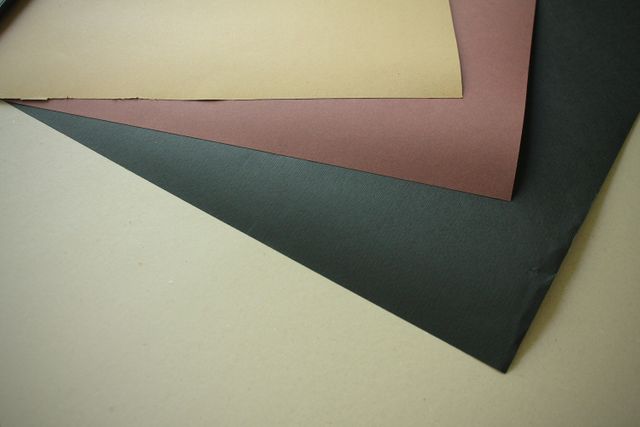 Assorted colored construction papers overlapping, featuring black, brown, and beige tones. Ideal for crafting scenes, school projects, or illustrating art supply materials. Perfect for educational content, DIY tutorials, and stationery shop advertisements.