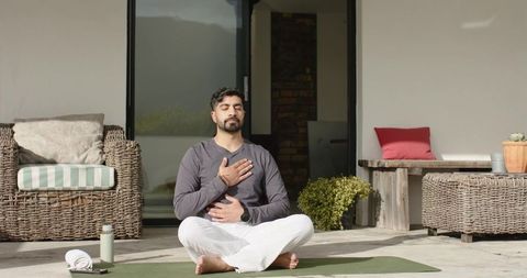 Indian man practicing mindful breathing on patio during morning meditation and outdoor yoga
