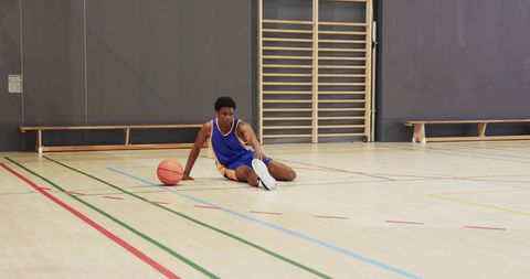 Athletic Basketball Player Resting on Indoor Court