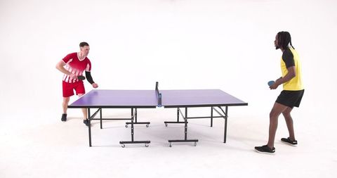 Diverse male athletes intently playing table tennis indoors
