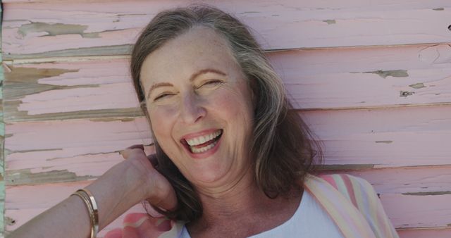 Laughing Mature Woman Posing Against Weathered Pink Wall - Download Free Stock Images Pikwizard.com