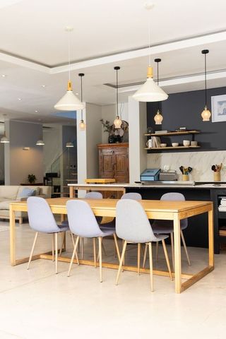 Showcasing modern open-plan dining with oak table, six grey chairs and pendant lighting