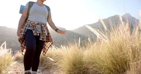 Woman Trekking Mountain Trail Touching Tall Grass