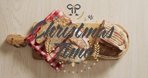 Rustic sourdough loaves on wooden paddle with checkered cloth and christmas time script