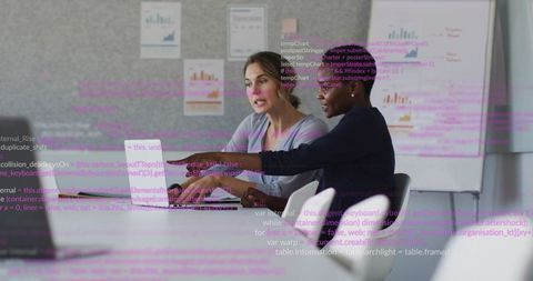 Two professionals reviewing data and code on laptop during collaborative office meeting