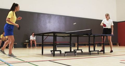 Women Engaging in Competitive Table Tennis Match