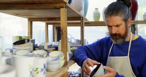Craftsman Inspecting Ceramic Bowl in Artisanal Pottery Studio - Download Free Stock Images Pikwizard.com