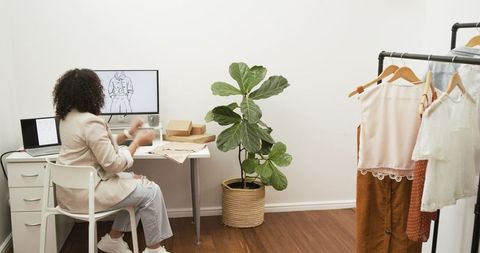 Fashion designer reviewing sketches and packing orders in small home studio