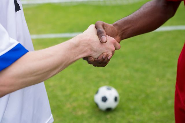 Cropped image of soccer player doing handshake while standing on playing field