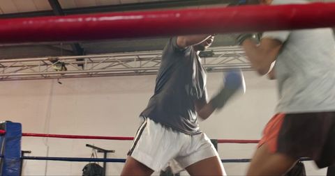 Male boxers sparring in gym ring training session showing power technique and motion