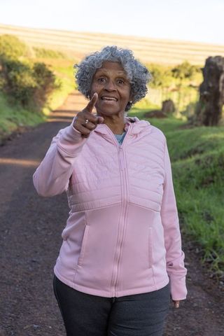 Senior Woman in Pink Jacket Outdoors Eagerly Pointing Forward