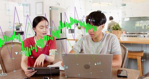 Young couple analyzing stock charts on laptop and tablet during home trading session