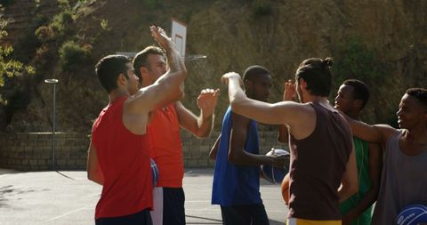 Group of Basketball Players Celebrating with High Fives Outdoors