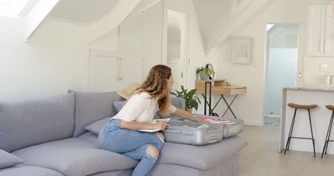 Young Woman Packing Suitcase in Cozy Modern Living Room