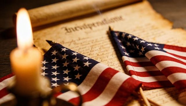 Candlelit american flags resting on independence document evoking patriotism and heritage