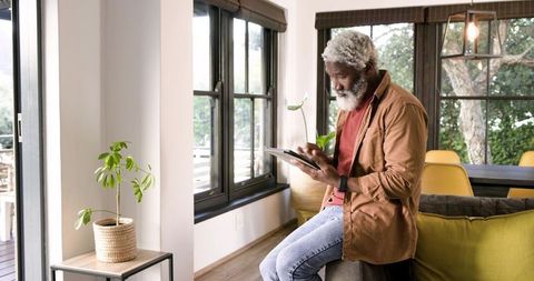 Senior man using tablet in modern living room interior