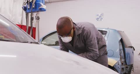 Mechanic Polishing Car with Grinder in Workshop